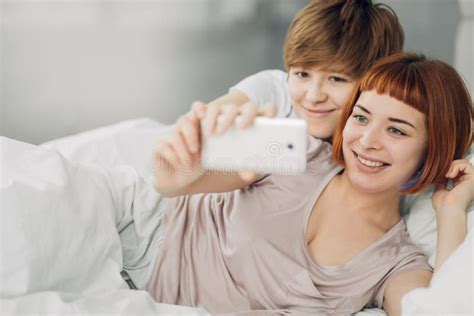 Duas lindas lésbicas sentam juntas na cama e se olham.
